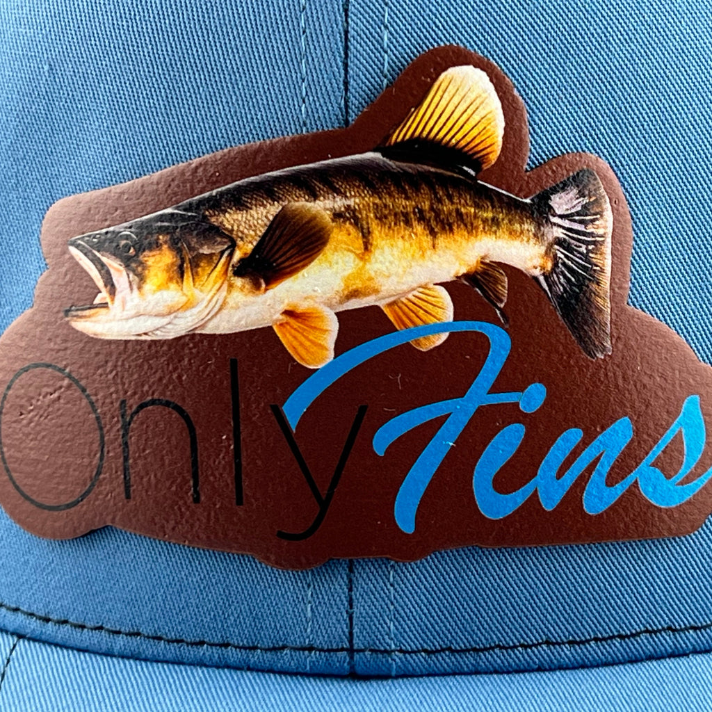 Close-up of the Only Fins walleye leather patch on a Columbia blue cap