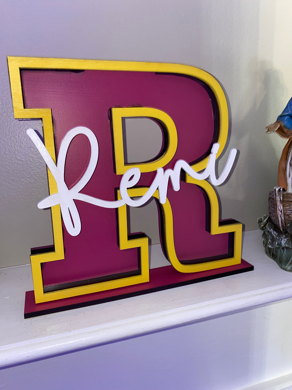 Maroon letter R name piggy bank with yellow trim and the name Remi